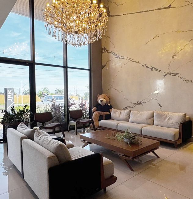 Sala principal do prédio da JRK Engenharia com sofás, mesa de centro e lustre elegante.